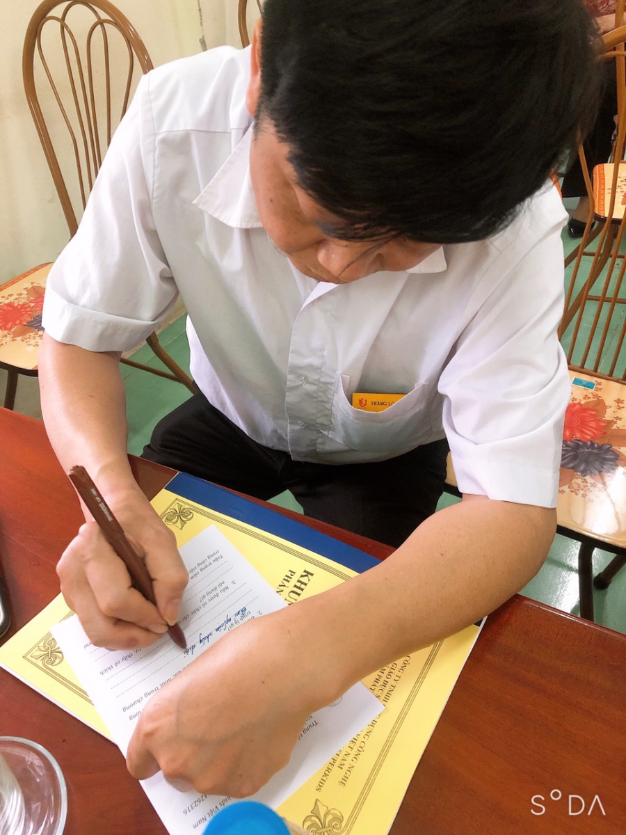 Thầy giáo đang chăm chú viết ra đánh giá của mình.